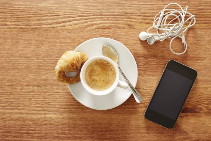 Having coffee and croissants with smartphone