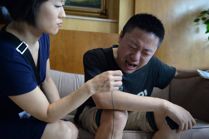 A relatives (R) of missing passengers who were on a ship which sank in the powerful Yangtze river the night before cries as he accepts an interview from a journalist outside a travel agency in Shanghai on June 2, 2015. China mounted a rescue operation on June 2 after the ship which was reportedly carrying more than 450 people sank in the powerful Yangtze river after being hit by stormy weather.   CHINA OUT     AFP PHOTO        (Photo credit should read STR/AFP/Getty Images)