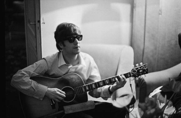 John Lennon (1940 - 1980) of the Beatles plays the guitar in a hotel room in Paris, 16th January 1964. (Photo by Harry Benson/Express/Hulton Archive/Getty Images)
