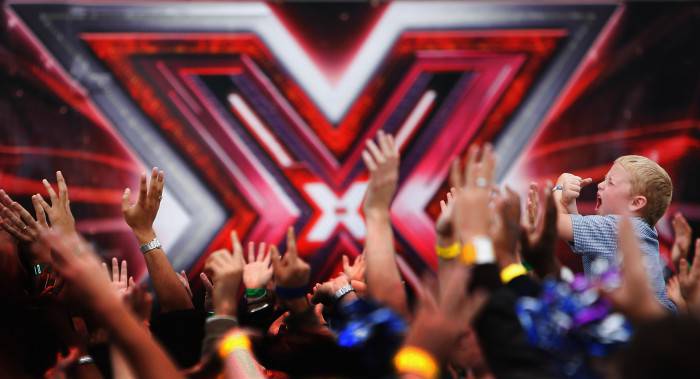 LONDON - JUNE 09:  A young boy holds up his arms in an X as contestants welcome the judges during the first day of auditions for series 4 X Factor at Arsenal Emirates Stadium on June 9, 2007 in London, England.  (Photo by Daniel Berehulak/Getty Images)