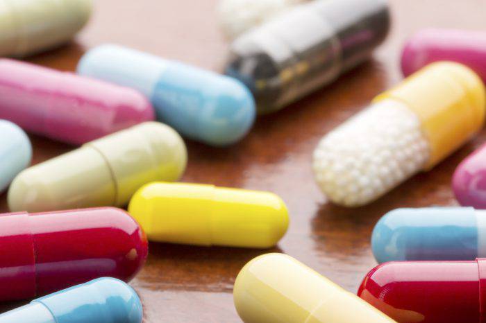 Various colorful medicine capsules on wooden table background